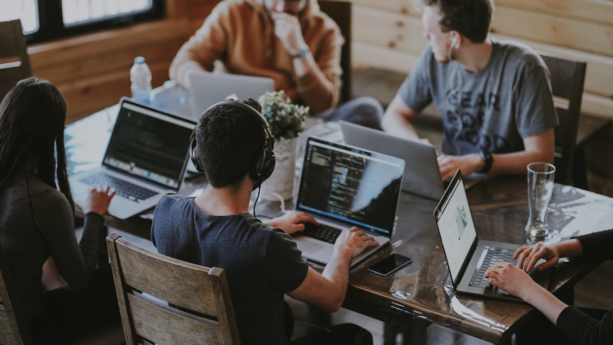 Colleagues gathered around a laptop at a shared work table.